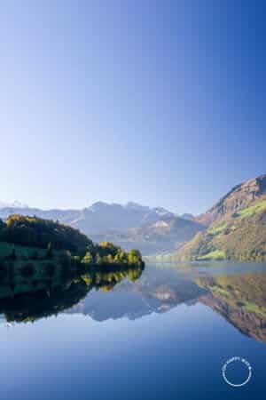 Reflexo de árvores e montanhas no lago Lungern, Suíça.