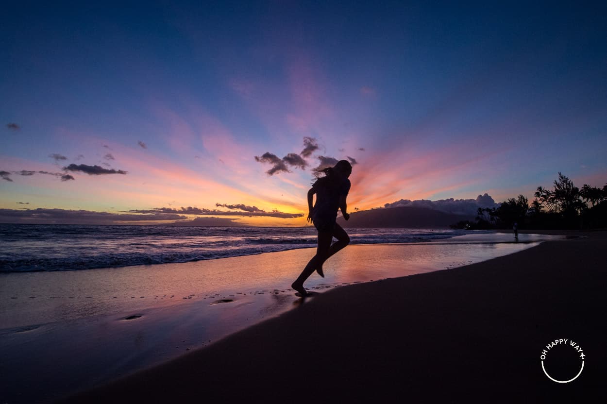 Silhueta de menina em frente ao pôr do sol em Maui, Havaí.