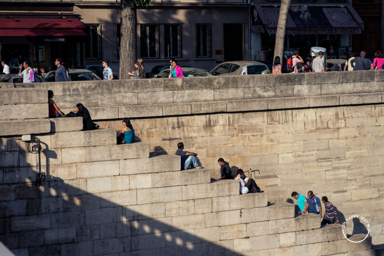 Pessoas sentadas em uma escada à beira do Rio Sena