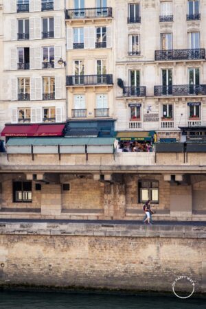 Pessoas caminhando próximas ao Rio Sena, em Paris.