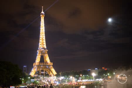 Lua e a Torre Eiffel iluminada à noite.