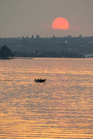 Pôr do sol e barco vistos do lago Paranoá, em Brasília