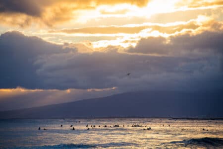 Pôr do sol no Hawaii: avião sobrevoando surfistas na praia de Waikiki, em Honolulu.