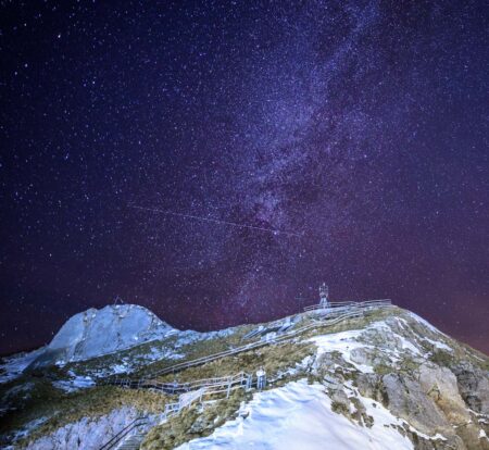 Avião cruzando o céu estrelado visto do monte Pilatus, na Suíça.