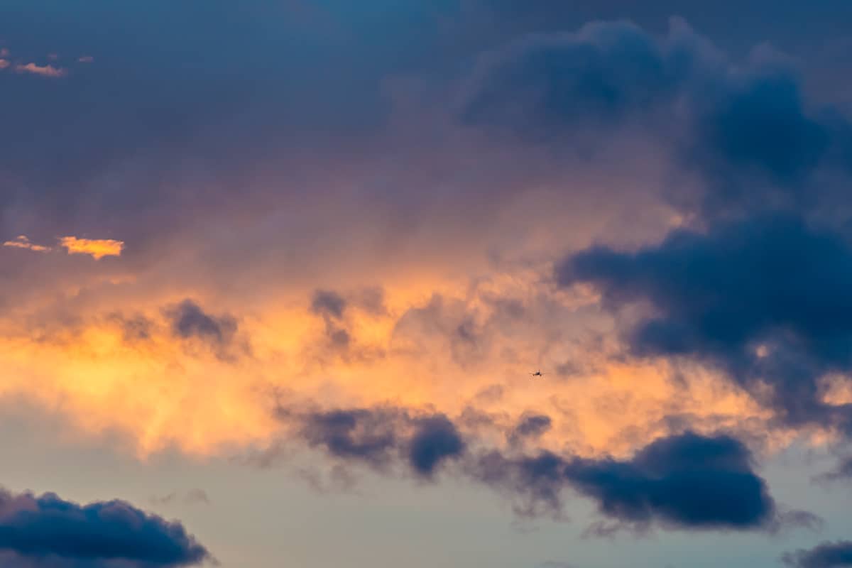 Avião passando por nuvens e pelo céu colorido