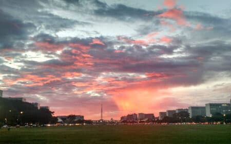 Nuvens e coluna de chuva iluminadas e coloridas pelo pôr do sol em Brasília