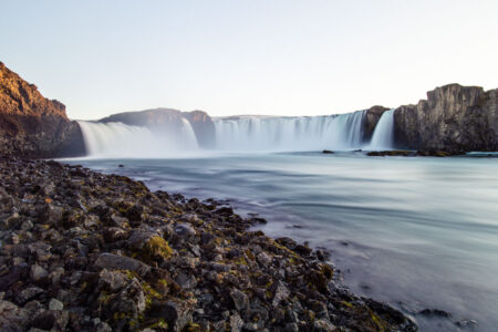 Pedras e longa exposição da cachoeira Godafoss, na Islândia