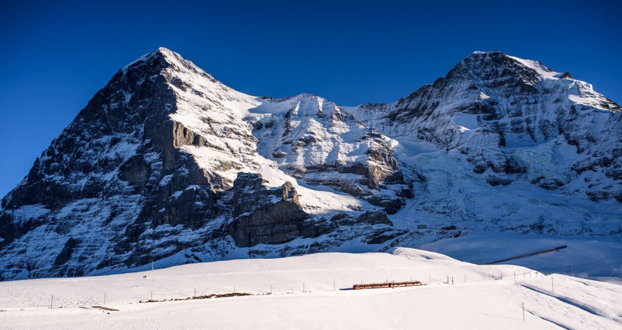 Trem passando em frente a uma montanha na subida para o monte Jungfrau, na Suíça.