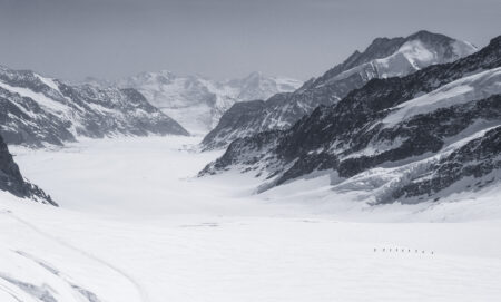 9 pessoas caminhando na neve próximas ao monte Jungfrau
