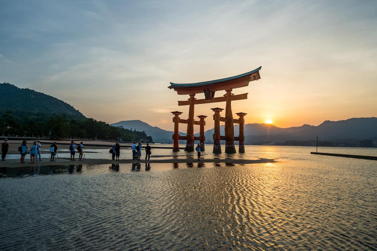 Torii em Miyajima em frente a montanhas e o sol